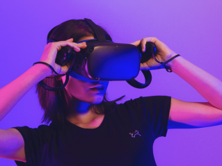 Persona con visore VR in un ambiente illuminato di blu e rosa.